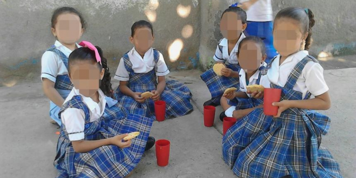 Las niñas reciben los alimentos en el piso.  
