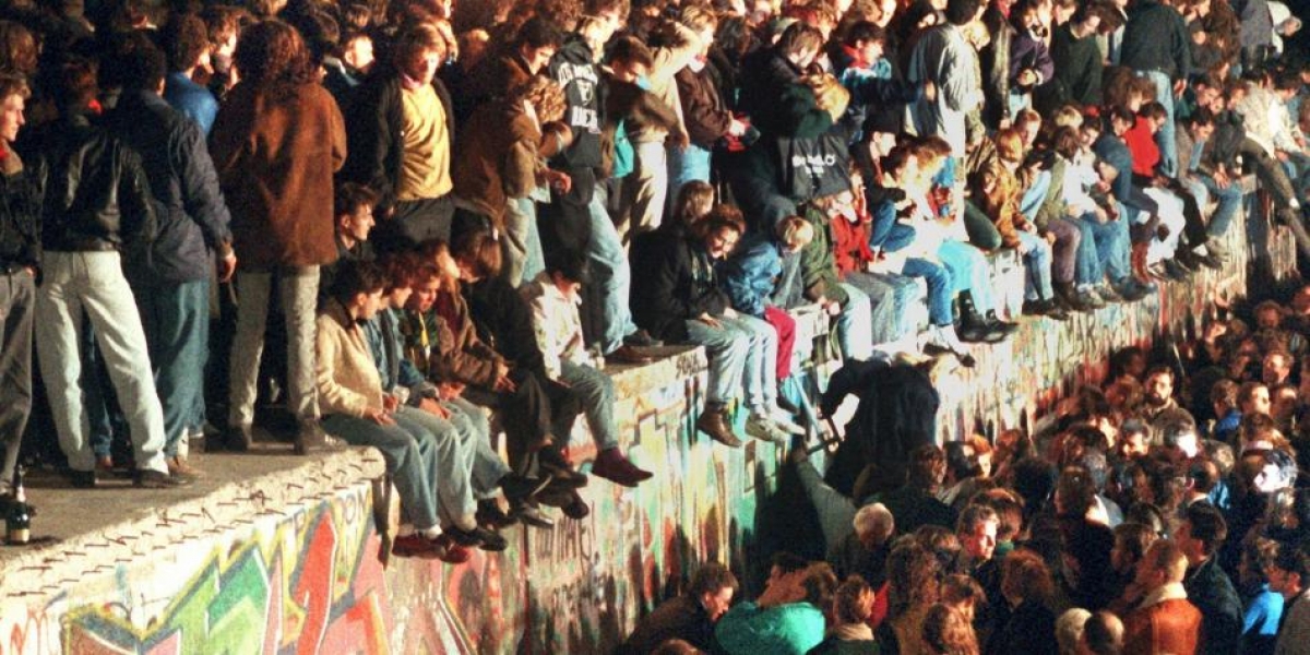 Jóvenes sobre el Muro de Berlín.
