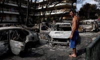  Un residente observa el estado en que han quedado varios coches calcinados tras el paso de las llamas por Mati, barrio del noreste de Atenas (Grecia) . 