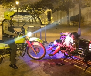 Momento en que el policía despierta a una mujer indigente y le pide que se vaya a otro lado.