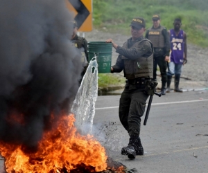 Miembros de la policía apagan una barricada en llamas durante una protesta el 3 de junio de 2017, en Buenaventura.