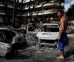  Un residente observa el estado en que han quedado varios coches calcinados tras el paso de las llamas por Mati, barrio del noreste de Atenas (Grecia) . 