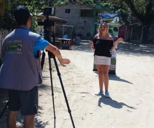 Daniela Salom, presentando para Travesía TV, medio de Gustavo Durán (de espaldas), quien la habría engañado y le niega el pago por su labor.