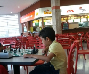 En la foto se ven las mesas vacías mientras los niños juegan ajedrez.