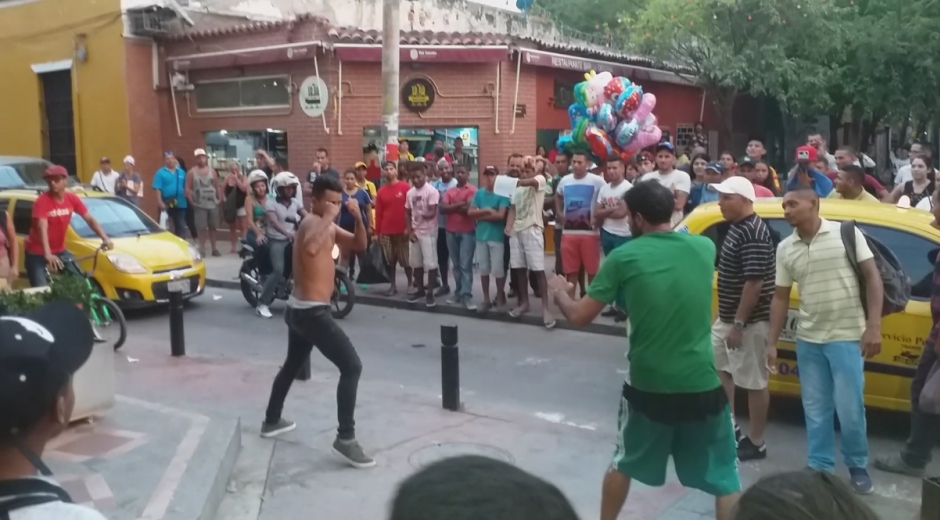Momento en que una de las personas del establecimiento comercial peleaba con el hombre de la calle (de verde).